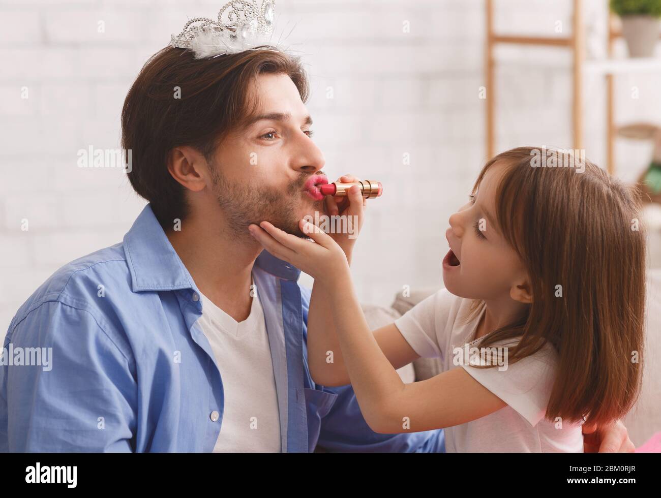 Kleines Mädchen, das Lippenstift auf ihre Papa Lippen legt Stockfoto