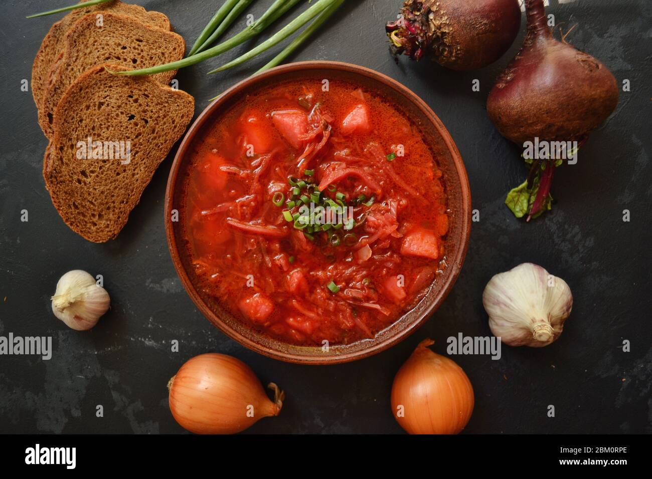 Hintergrund Essen auf dem Tisch. Ukrainische und russische Küche. Roter Borsch auf schwarzem Hintergrund. Borscht mit Gemüse und Tomaten. Rüben, Zwiebeln Stockfoto