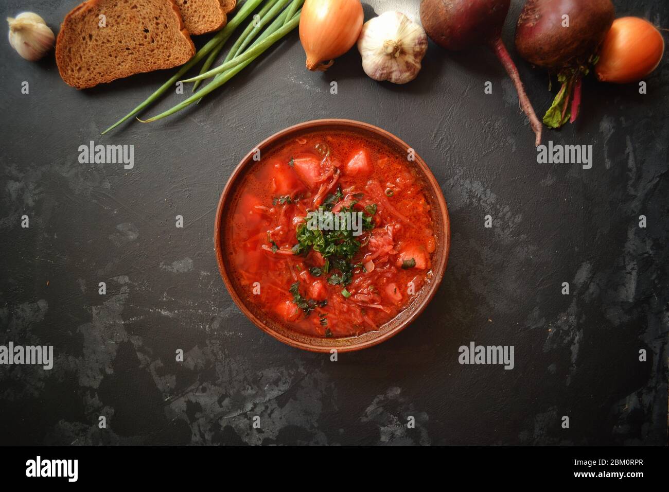 Hintergrund Essen auf dem Tisch. Ukrainische und russische Küche. Roter Borsch auf schwarzem Hintergrund. Borscht mit Gemüse und Tomaten. Rüben, Zwiebeln Stockfoto
