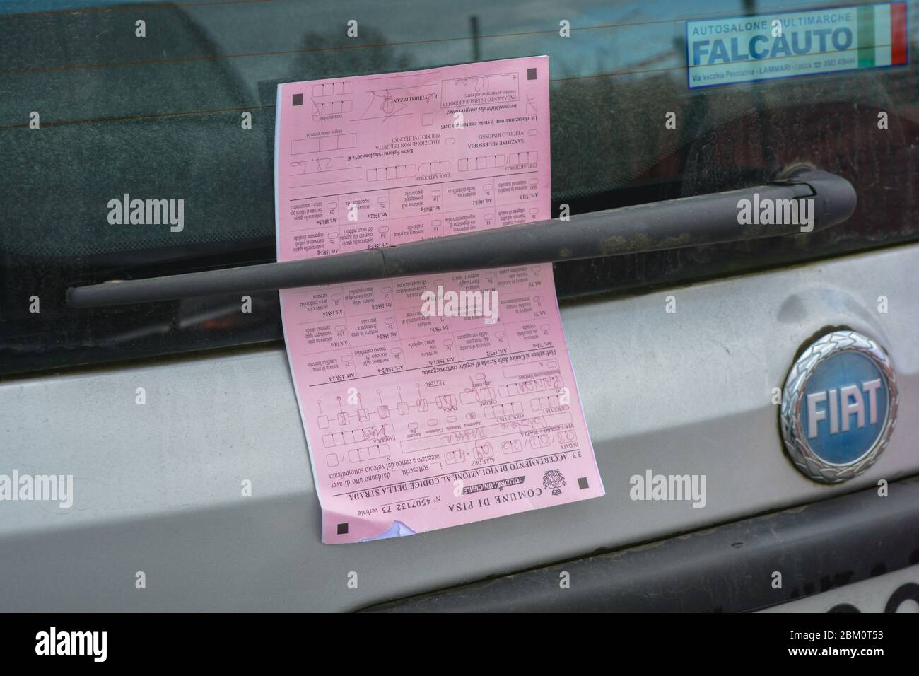 Ein Parkschein, eine Geldstrafe (Multa), die von der Polizei (Polizeikommunale o Vigili Urbani) für einen Fiat Pands Auto ausgestellt wurde, der auf einem Kreisverkehr geparkt ist. Stockfoto