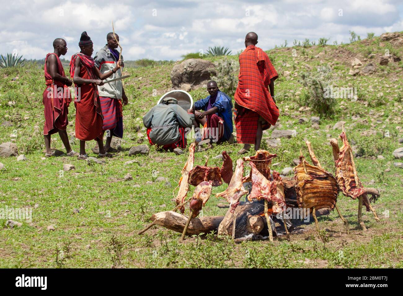 Kenia, Masai Mara, Masai (auch Maasai) Stammesmann kocht Fleisch auf offenem Feuer Stockfoto