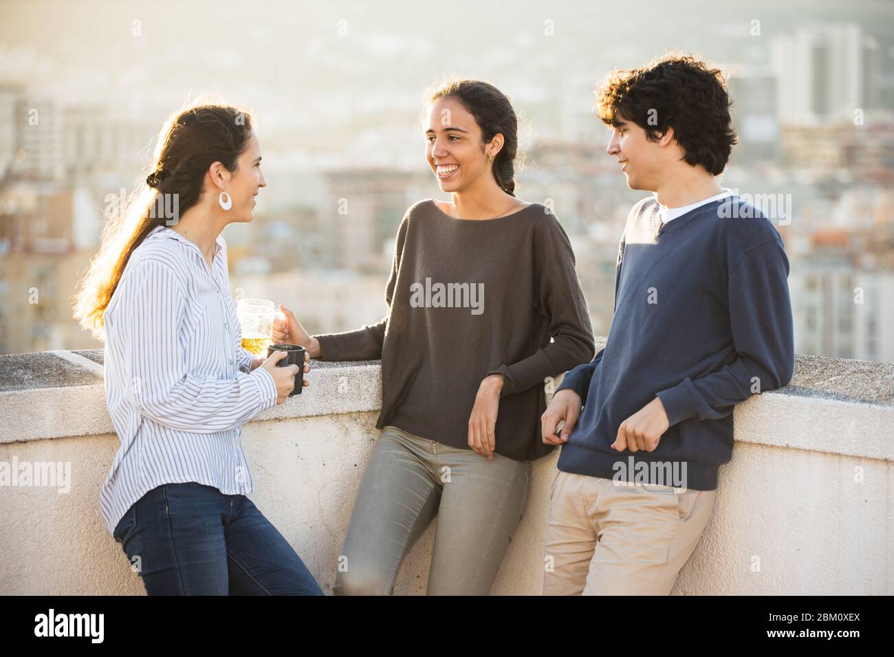 Drei junge Leute plaudern und machen einen Snack auf dem Dach Stockfoto