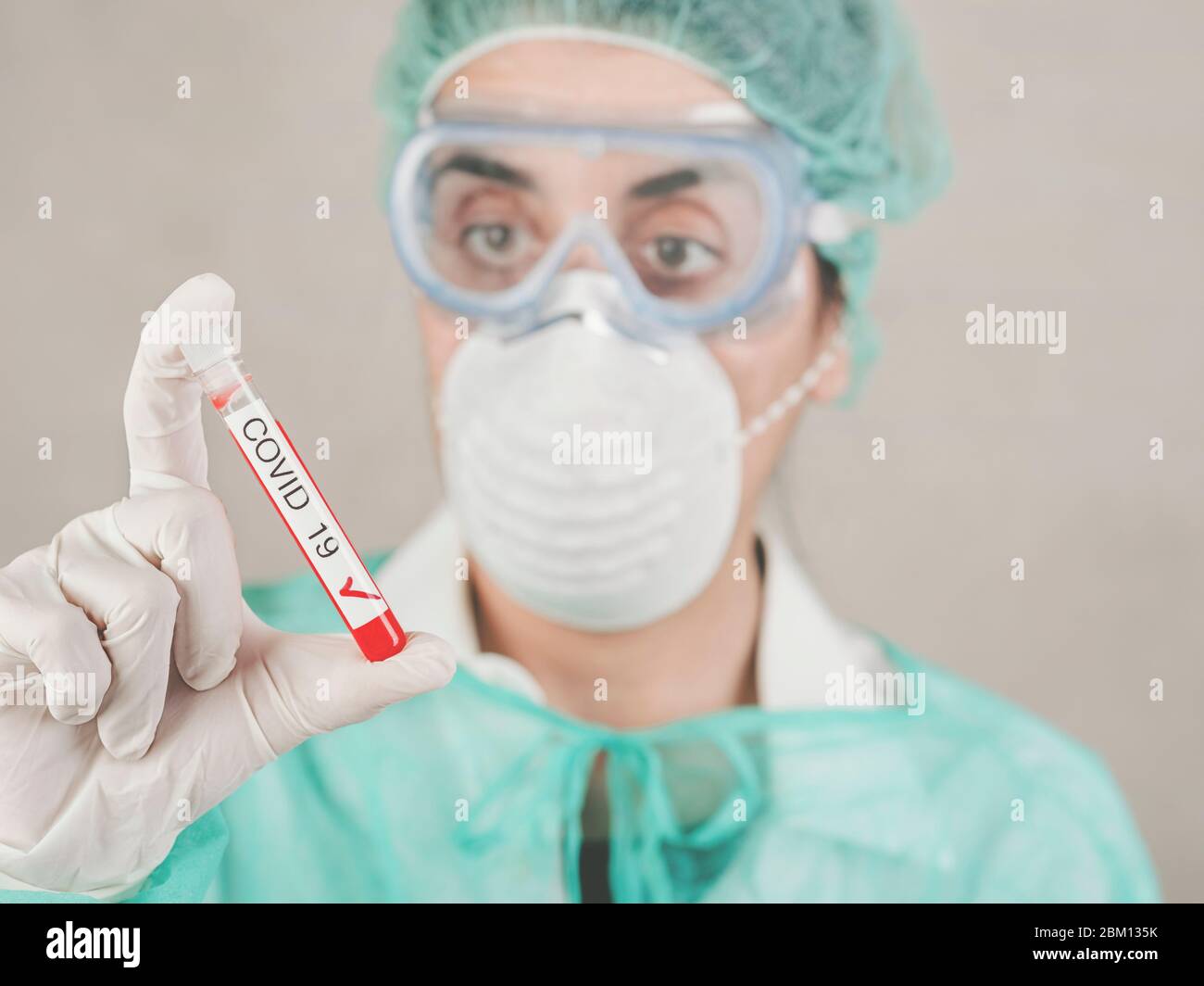 Coronavirus.Mediziner Arzt hält Reagenzglas mit Blut für 2019-nCoV über grauem Hintergrund, Hintergrund verschwommen Stockfoto