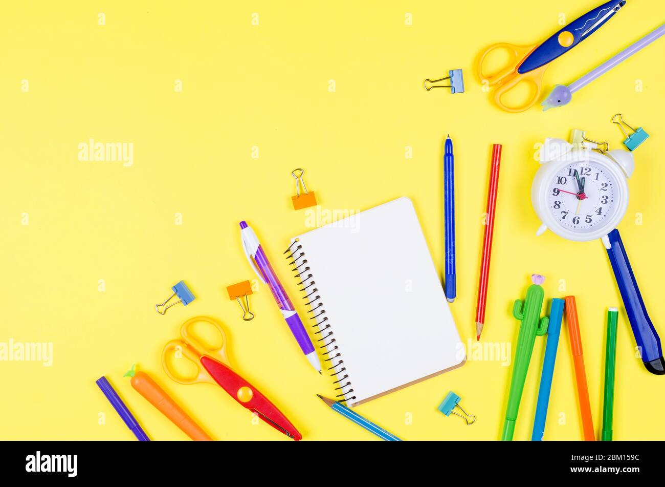 Farbige verschiedene Schulbedarf auf weichem gelben Papier Hintergrund. Notizbuch, Stifte, Bleistifte und andere Werkzeuge. Zurück zur Schule. Flaches Lay, oben V Stockfoto