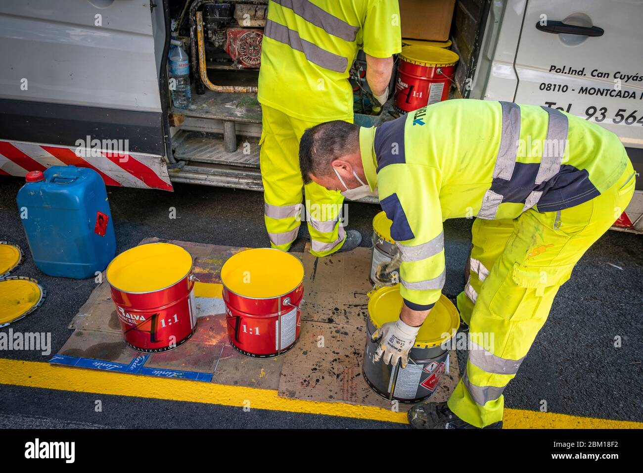 Die Betreiber werden gesehen, wie sie den Farbmix vorbereiten, um während der Coronavirus-Krise eine neue Fahrradspur auf der Straße zu signalisieren.der Stadtrat von Barcelona implementiert 21 km einer neuen Fahrradspur und 12 km neuer Gehwege für Fußgänger, um Bewegungen mit obligatorischer Distanz in der "Post-Covid-19 Ära zu erleichtern. Stockfoto
