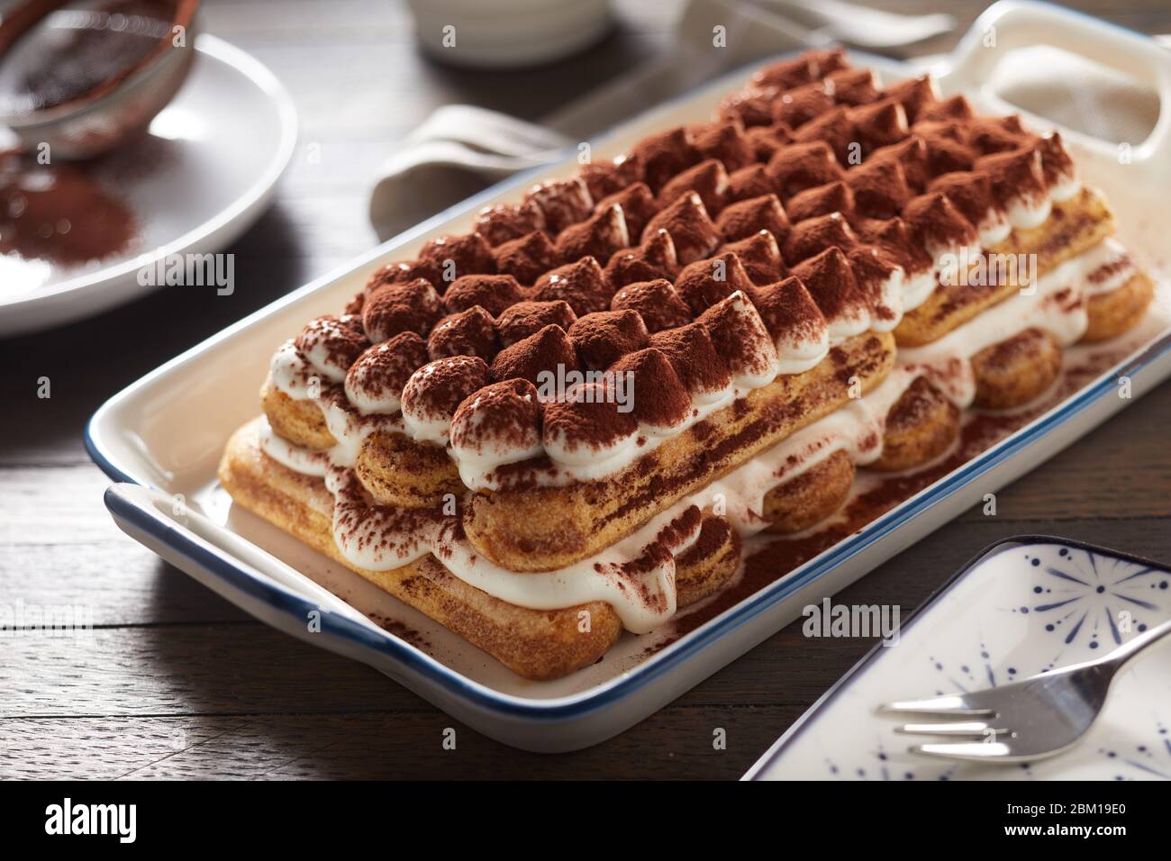 Ganz frisch zubereitetes italienisches Tiramisu-Dessert auf einer großen Platte, serviert am Tisch in einem Nahaufnahme für regionale Küche Stockfoto