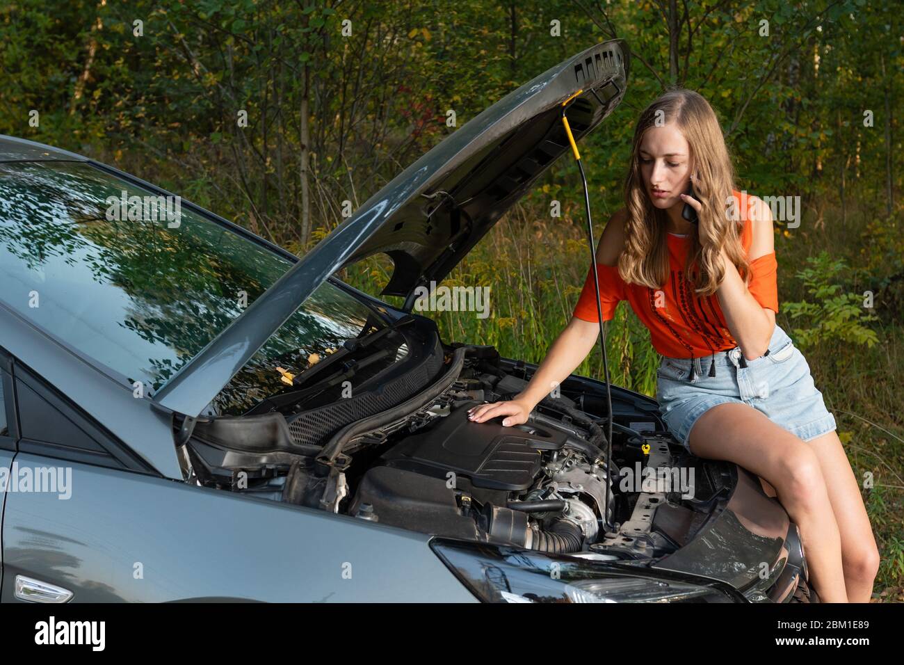 Junge Frau in der Nähe von Broken Auto sprechen per Telefon Unterstützung benötigt - Bild Stockfoto