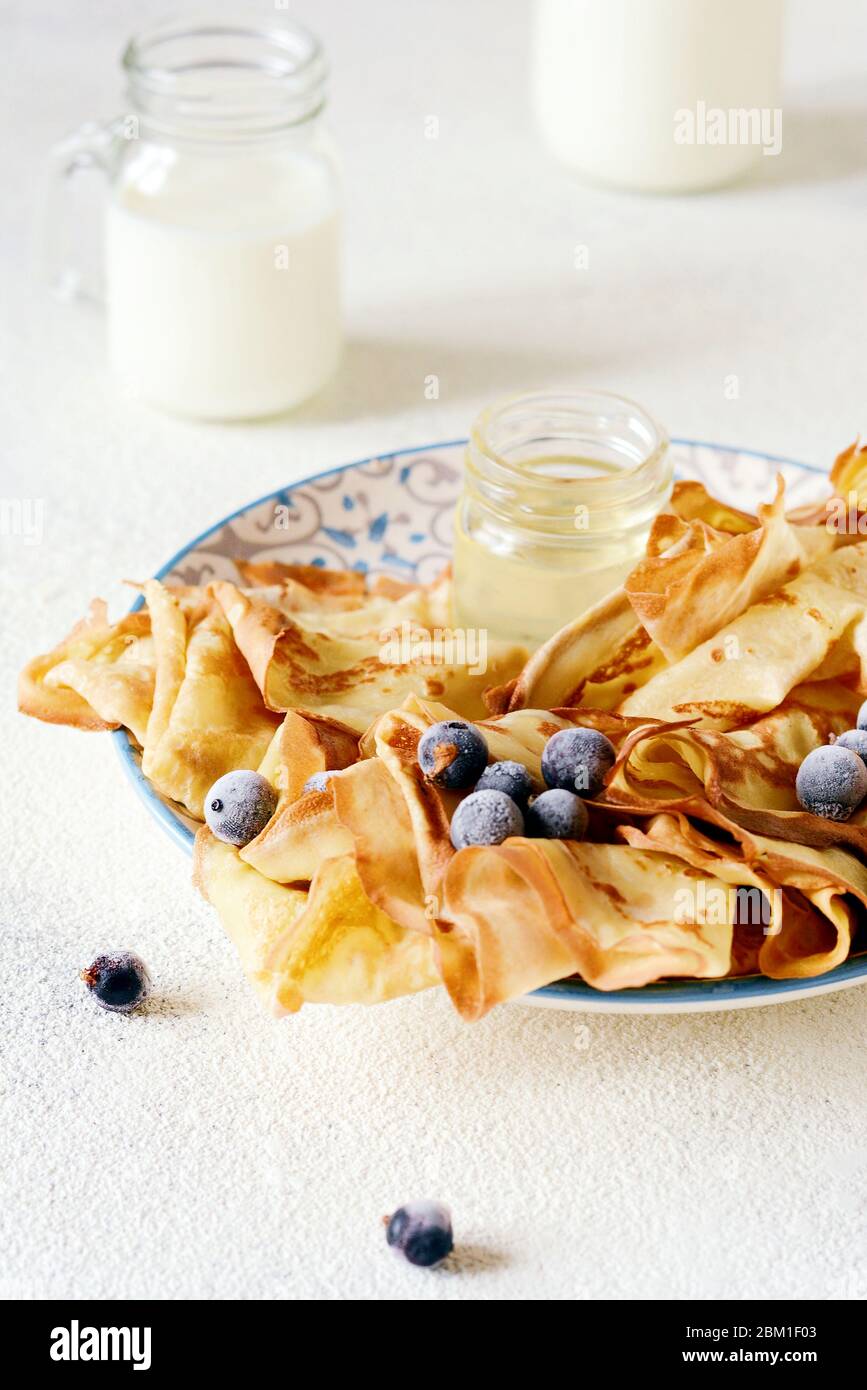 Hausgemachte dünne Pfannkuchen mit Beeren, Honig und Milch zum ...