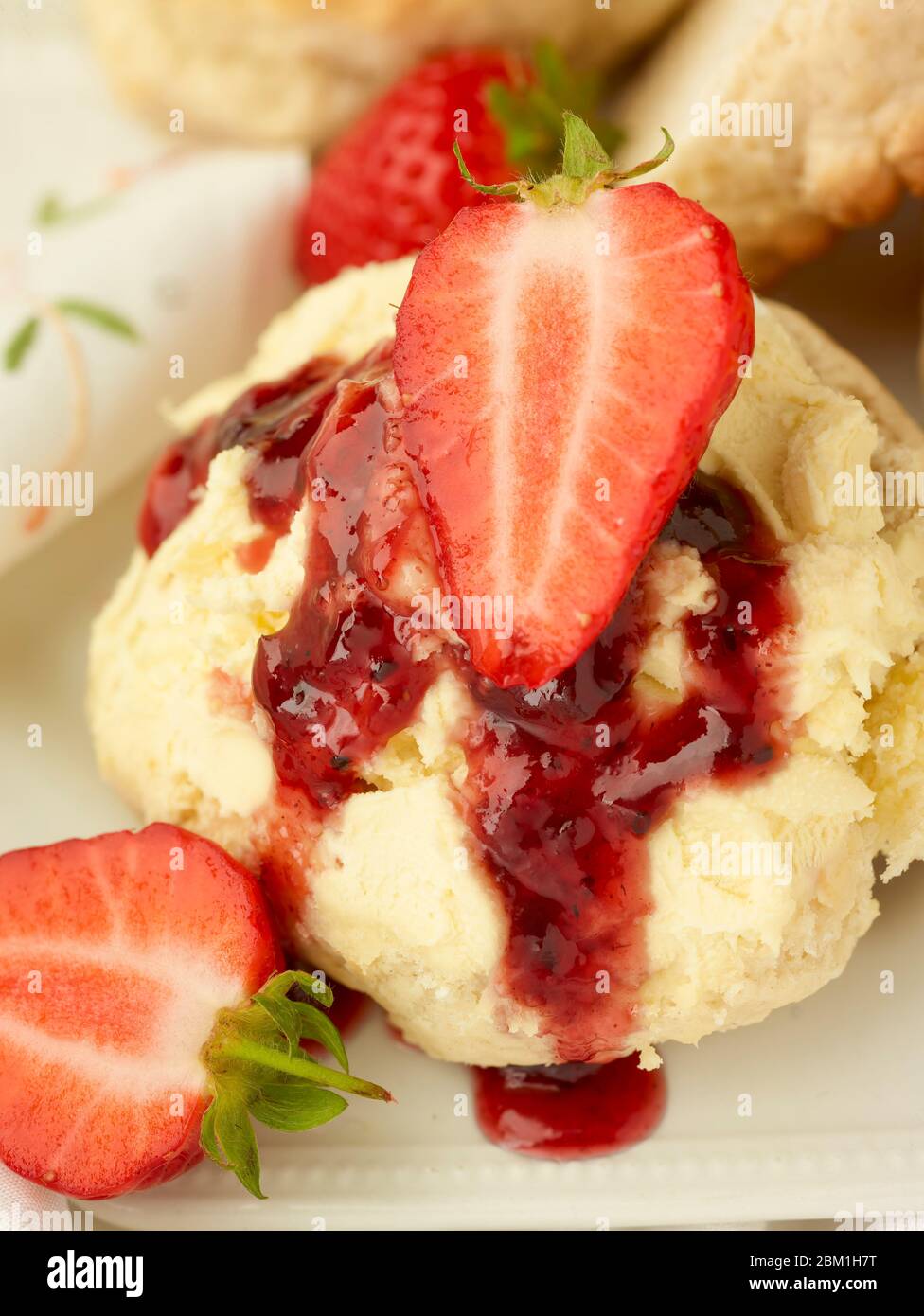 Britischer Sahnetee, Scones mit gerinnter Sahne, Erdbeermarmelade und Erdbeeren auf weißem Hintergrund, Food Stillleben Stockfoto