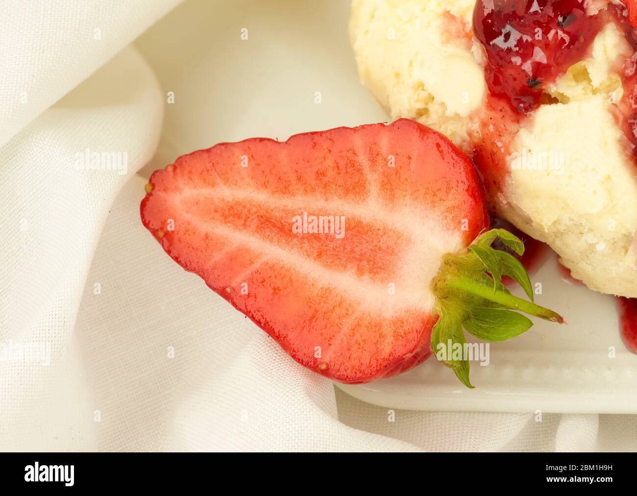 Britischer Sahnetee, Scones mit gerinnter Sahne, Erdbeermarmelade und Erdbeeren auf weißem Hintergrund, Food Stillleben Stockfoto