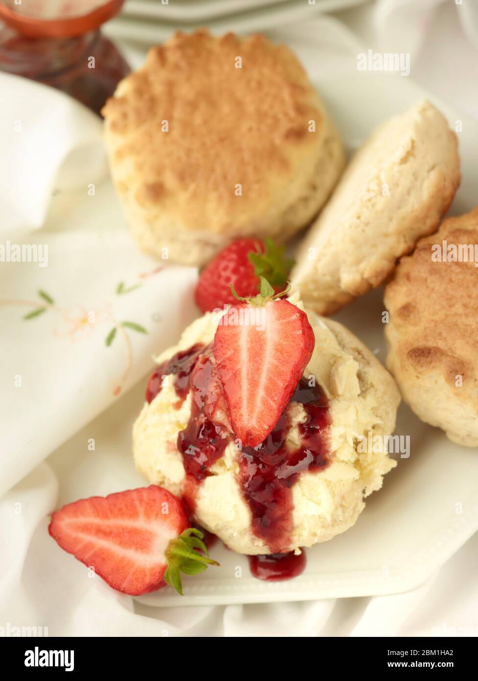 Britischer Sahnetee, Scones mit gerinnter Sahne, Erdbeermarmelade und Erdbeeren auf weißem Hintergrund, Food Stillleben Stockfoto