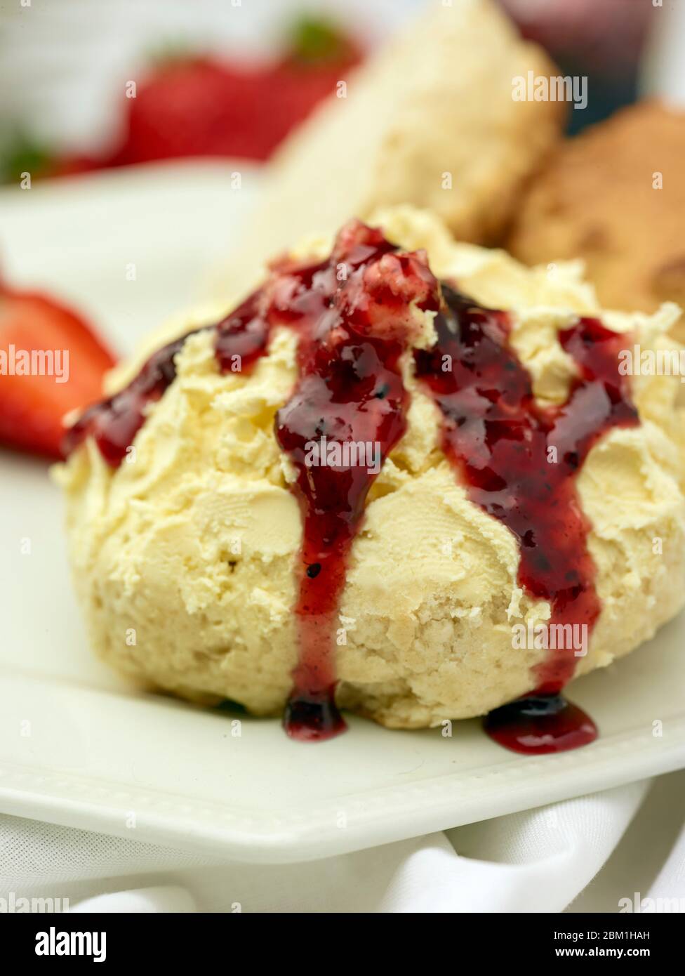 Britischer Sahnetee, Scones mit gerinnter Sahne, Erdbeermarmelade und Erdbeeren auf weißem Hintergrund, Food Stillleben Stockfoto