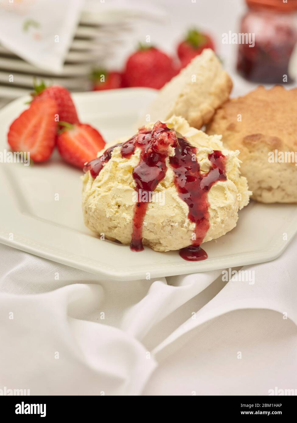 Britischer Sahnetee, Scones mit gerinnter Sahne, Erdbeermarmelade und Erdbeeren auf weißem Hintergrund, Food Stillleben Stockfoto