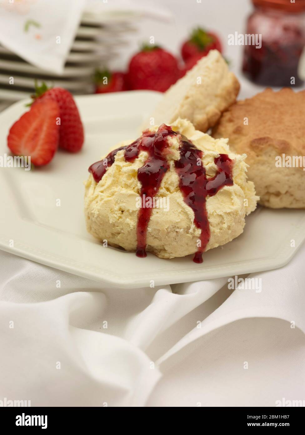 Britischer Sahnetee, Scones mit gerinnter Sahne, Erdbeermarmelade und Erdbeeren auf weißem Hintergrund, Food Stillleben Stockfoto