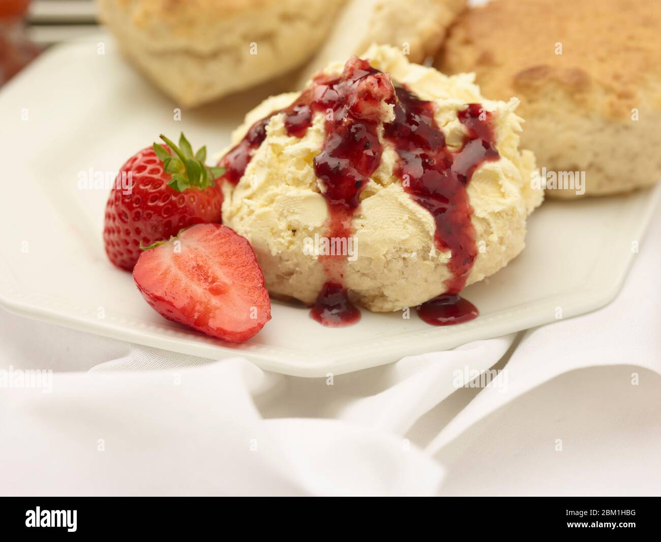 Britischer Sahnetee, Scones mit gerinnter Sahne, Erdbeermarmelade und Erdbeeren auf weißem Hintergrund, Food Stillleben Stockfoto