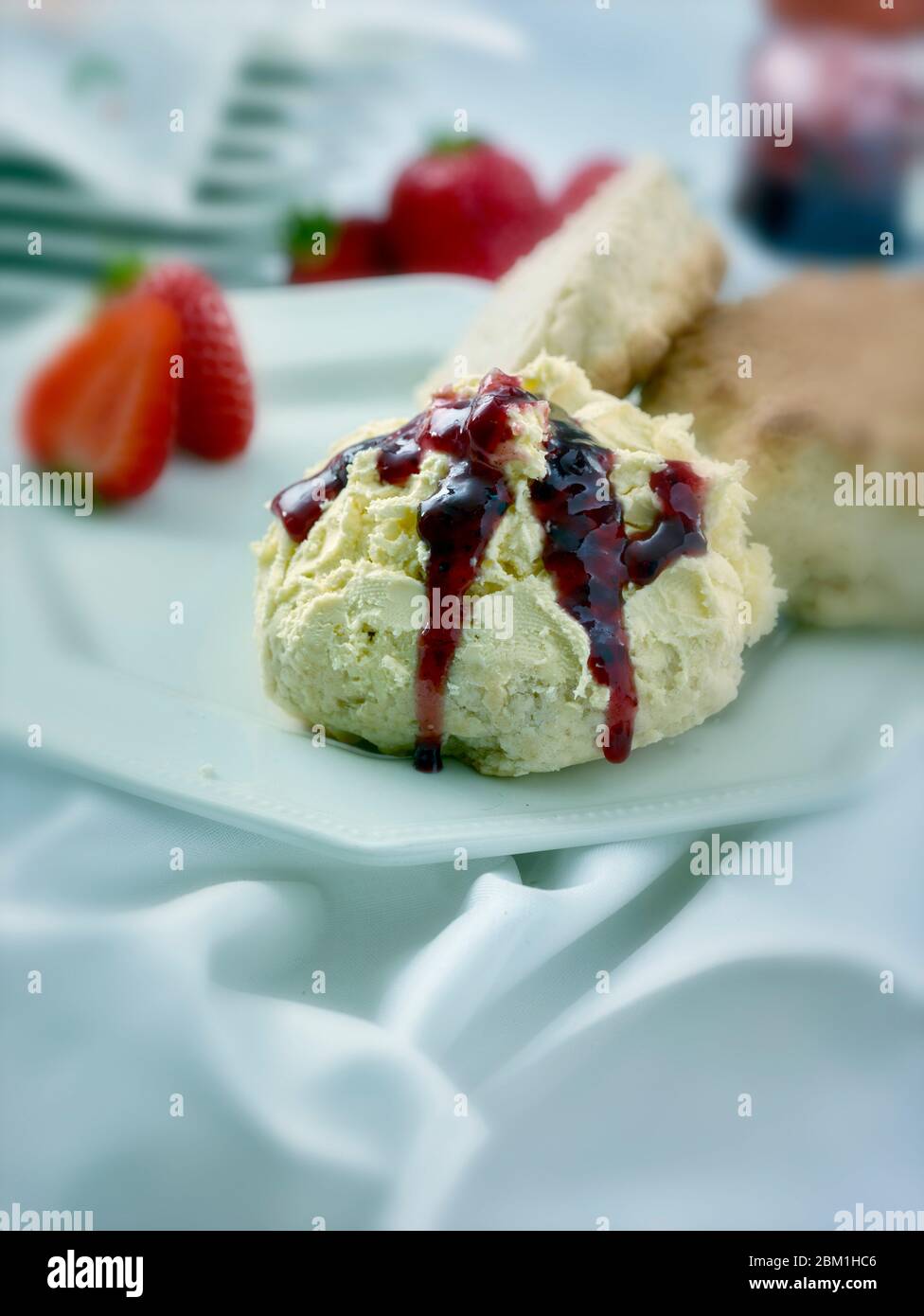 Britischer Sahnetee, Scones mit gerinnter Sahne, Erdbeermarmelade und Erdbeeren auf weißem Hintergrund, Food Stillleben Stockfoto