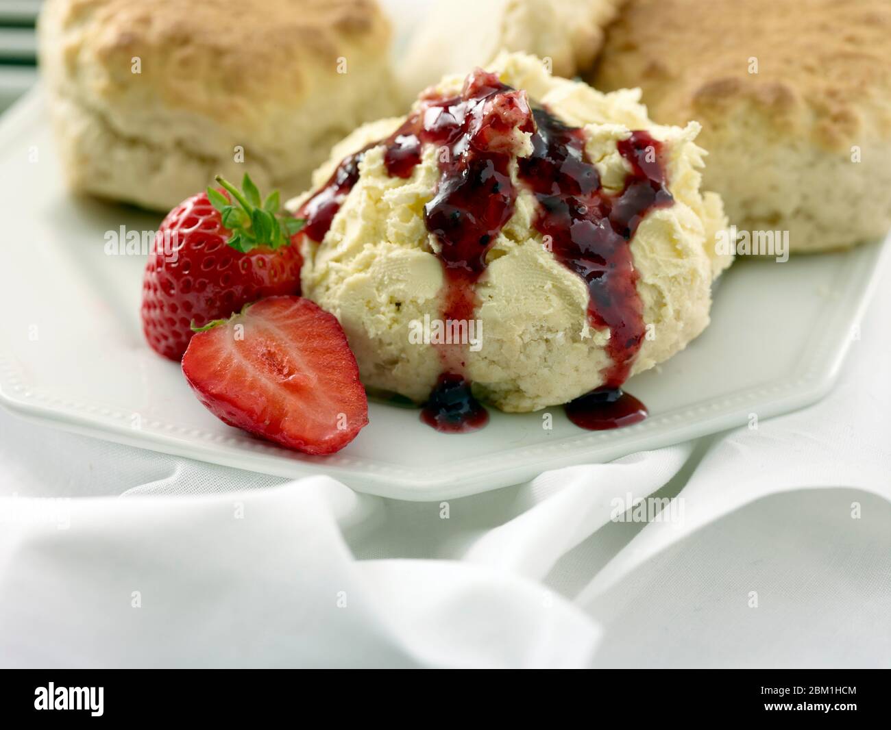 Britischer Sahnetee, Scones mit gerinnter Sahne, Erdbeermarmelade und Erdbeeren auf weißem Hintergrund, Food Stillleben Stockfoto