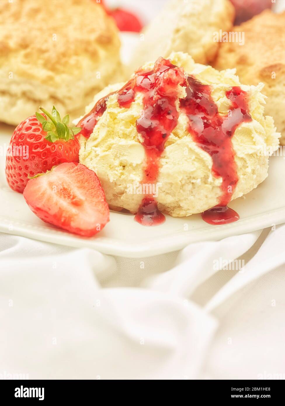 Britischer Sahnetee, Scones mit gerinnter Sahne, Erdbeermarmelade und Erdbeeren auf weißem Hintergrund, Food Stillleben Stockfoto