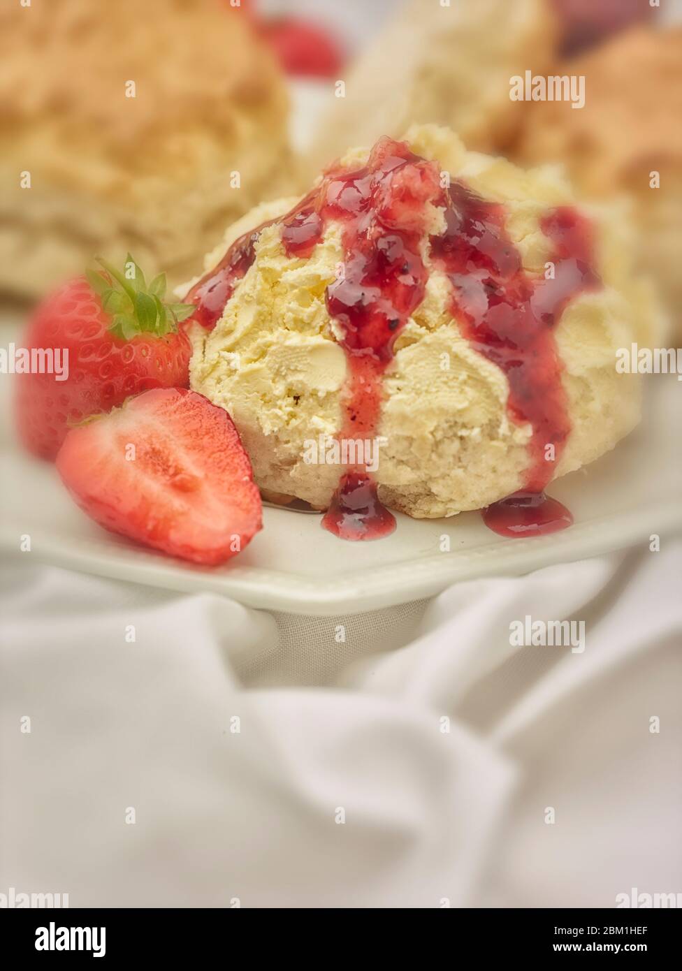 Britischer Sahnetee, Scones mit gerinnter Sahne, Erdbeermarmelade und Erdbeeren auf weißem Hintergrund, Food Stillleben Stockfoto