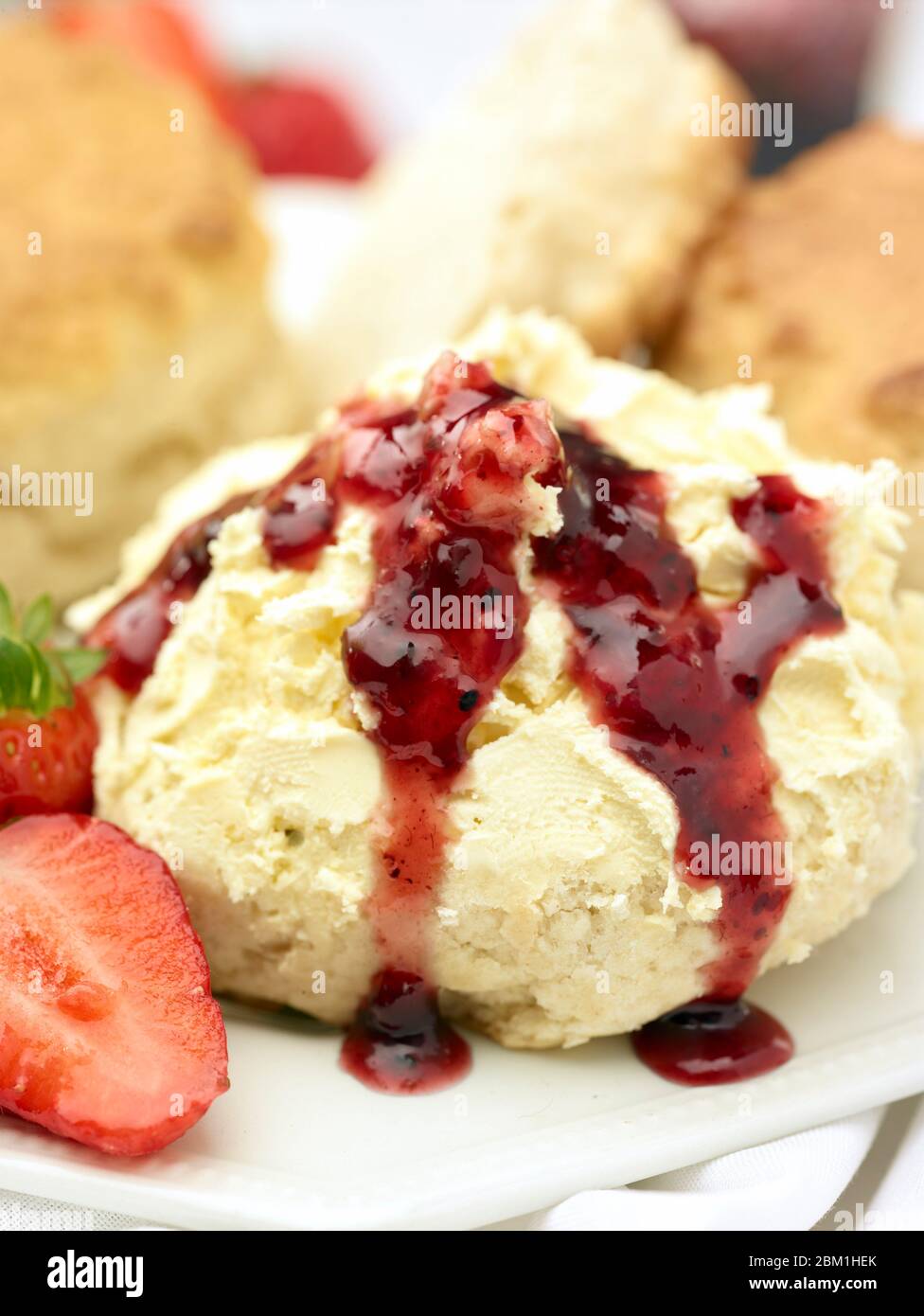 Britischer Sahnetee, Scones mit gerinnter Sahne, Erdbeermarmelade und Erdbeeren auf weißem Hintergrund, Food Stillleben Stockfoto