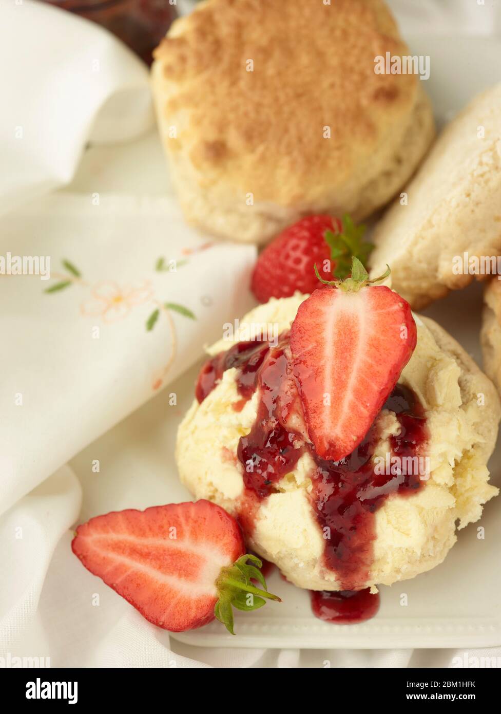 Britischer Sahnetee, Scones mit gerinnter Sahne, Erdbeermarmelade und Erdbeeren auf weißem Hintergrund, Food Stillleben Stockfoto
