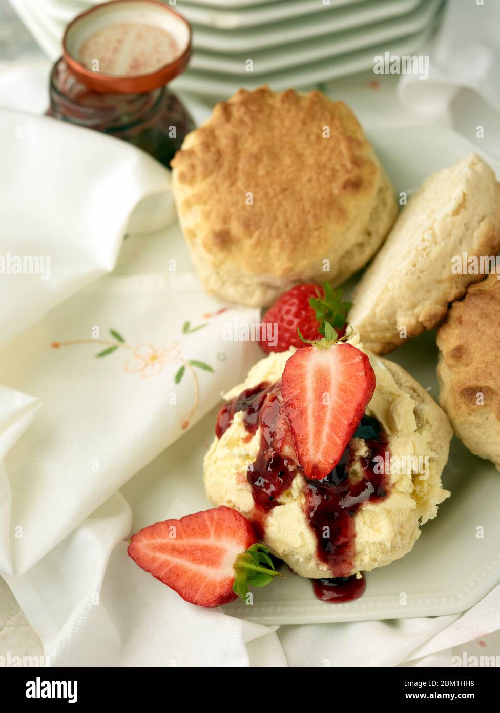 Britischer Sahnetee, Scones mit gerinnter Sahne, Erdbeermarmelade und Erdbeeren auf weißem Hintergrund, Food Stillleben Stockfoto