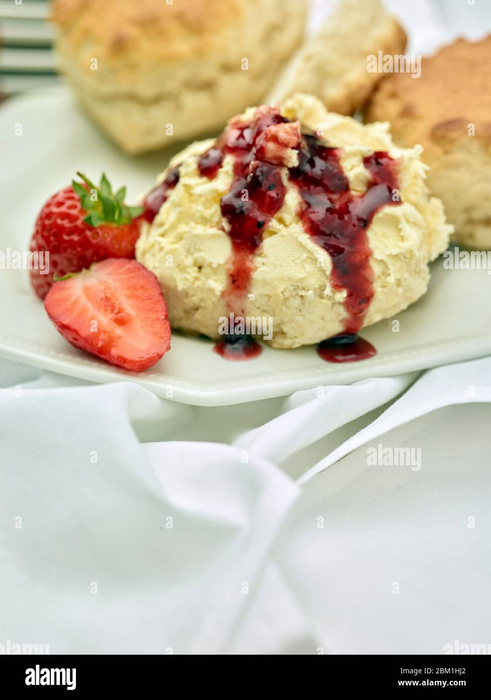 Britischer Sahnetee, Scones mit gerinnter Sahne, Erdbeermarmelade und Erdbeeren auf weißem Hintergrund, Food Stillleben Stockfoto