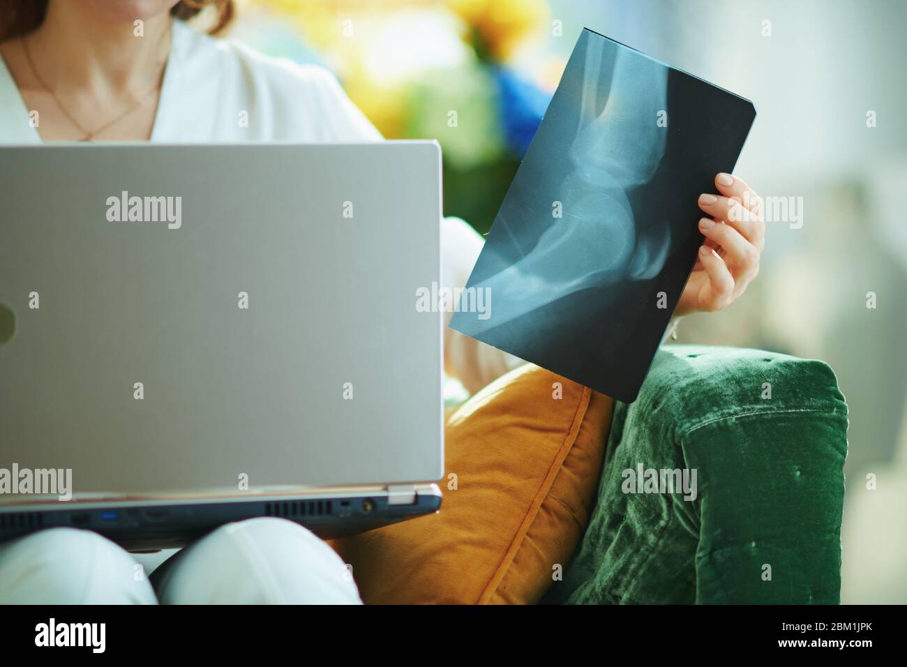 Nahaufnahme auf Frau mit Röntgenaufnahme im Wohnzimmer mit Arzt mit telemedizinischer Technologie an sonnigen Tagen. Stockfoto