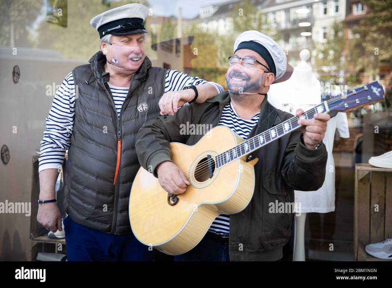 Hamburg, Deutschland. Mai 2020. Claas Vogt (l.) und Klaus Baumgart (Musikerduo Klaus & Klaus) stehen mit ihren neuen Fotomasken als Mund-Nase-Schutz vor der Textildruckerei "Impression". Kredit: Christian Charisius/dpa/Alamy Live News Stockfoto
