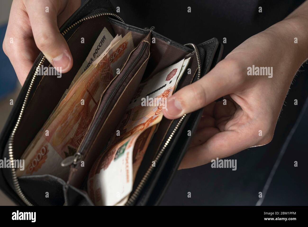 Ein Mann mit einer schwarzen Brieftasche voller russisches Geld. In einer schwarzen Brieftasche, Banknoten sind meist 5,000 Rubel pro Stück. Gehalt und Rente erhöht, Leistungen Stockfoto