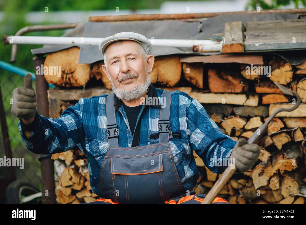 Senior Smiling man schärft Werkzeug für die Kultivierung von Bauernboden. Landwirtschaftskonzept Stockfoto