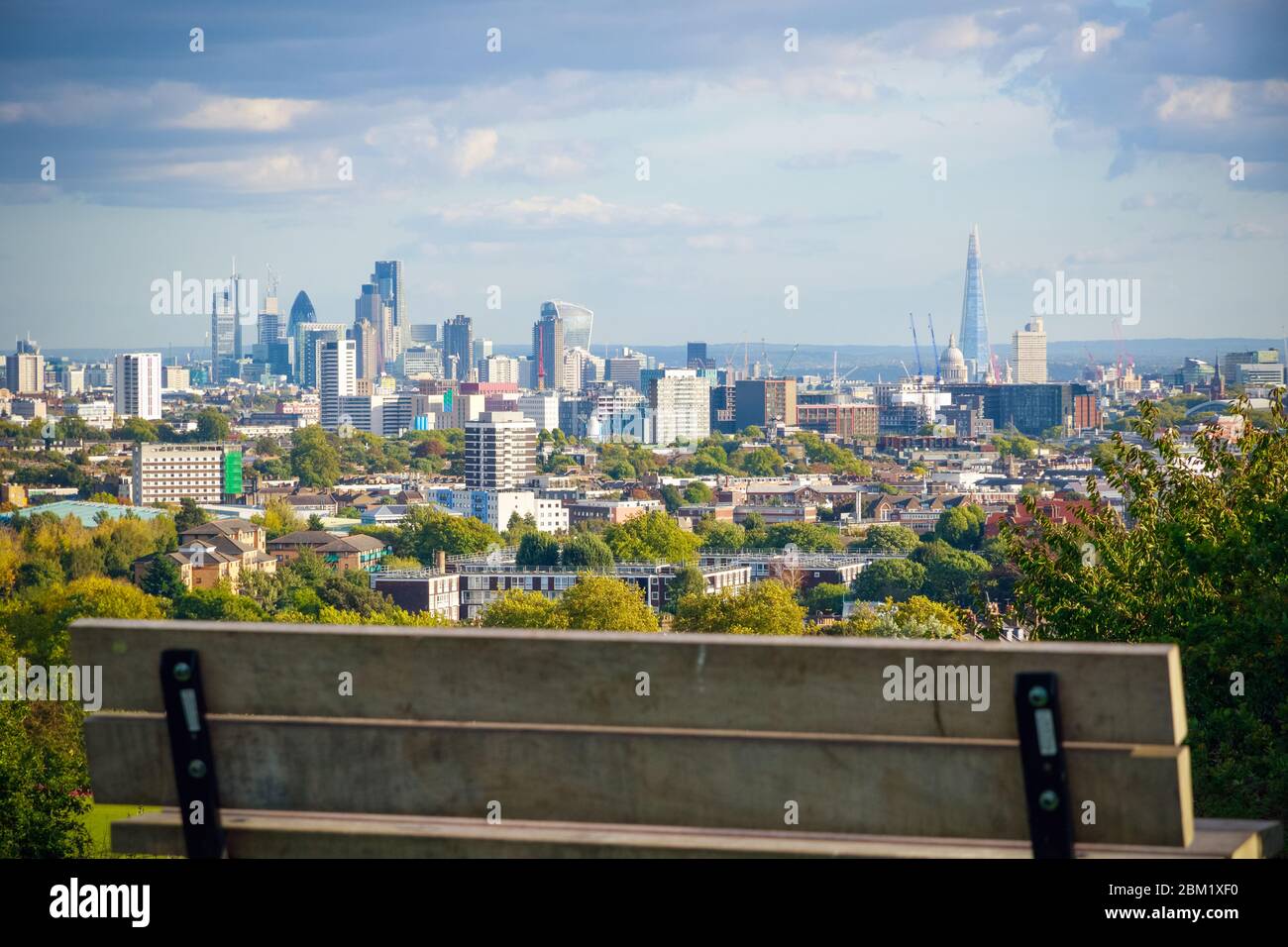 Blick auf die Skyline von London vom Parliament Hill in Hampstead Heath durch eine leere Bank Stockfoto