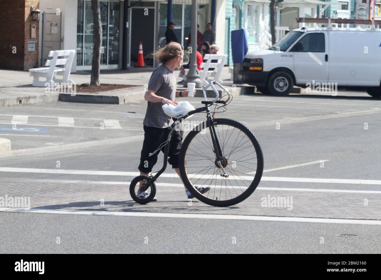 Mann mit einem High Wheeler (Penny-Farthing) Fahrrad auf der Straße in den USA Stockfoto