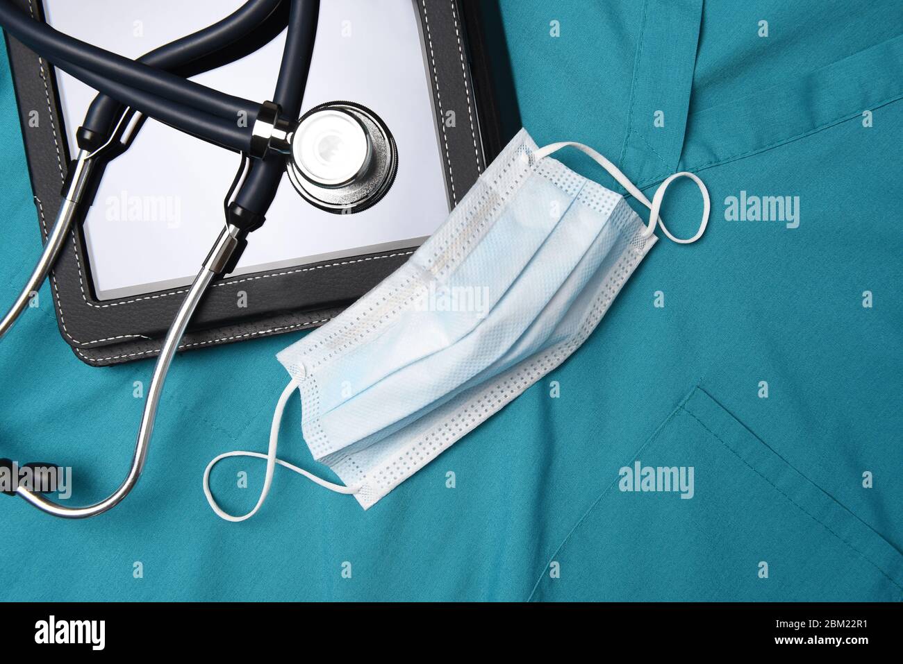 Stethoskop, chirurgische Maske und medizinische Tablet-Computer auf einem Satz von chirurgischen Grüns, Scrubs. Stockfoto