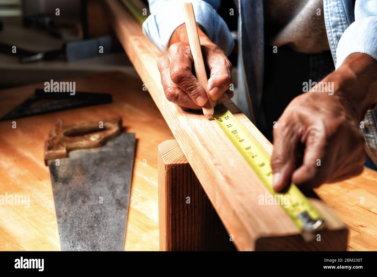 Nahaufnahme eines Holzarbeiters in seiner Werkstatt, der ein Brett zum Schneiden markiert. Stockfoto