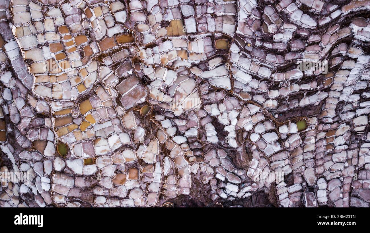 Luftaufnahme der Salzverdunstungsteiche in der Salzmine in Maras, Peru. Verschiedene Formen und Farben von Teichen schaffen das abstrakte Muster und die Form. Stockfoto