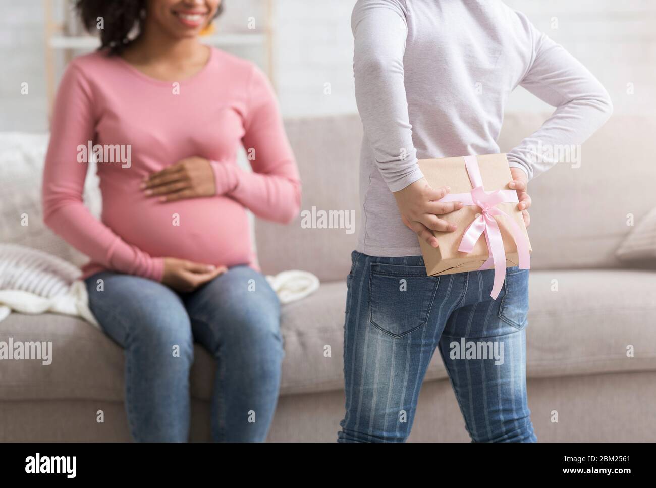 Kleine Tochter Holding Überraschung Geschenk Für Sie Schwanger Mutter Hinter Zurück Stockfoto