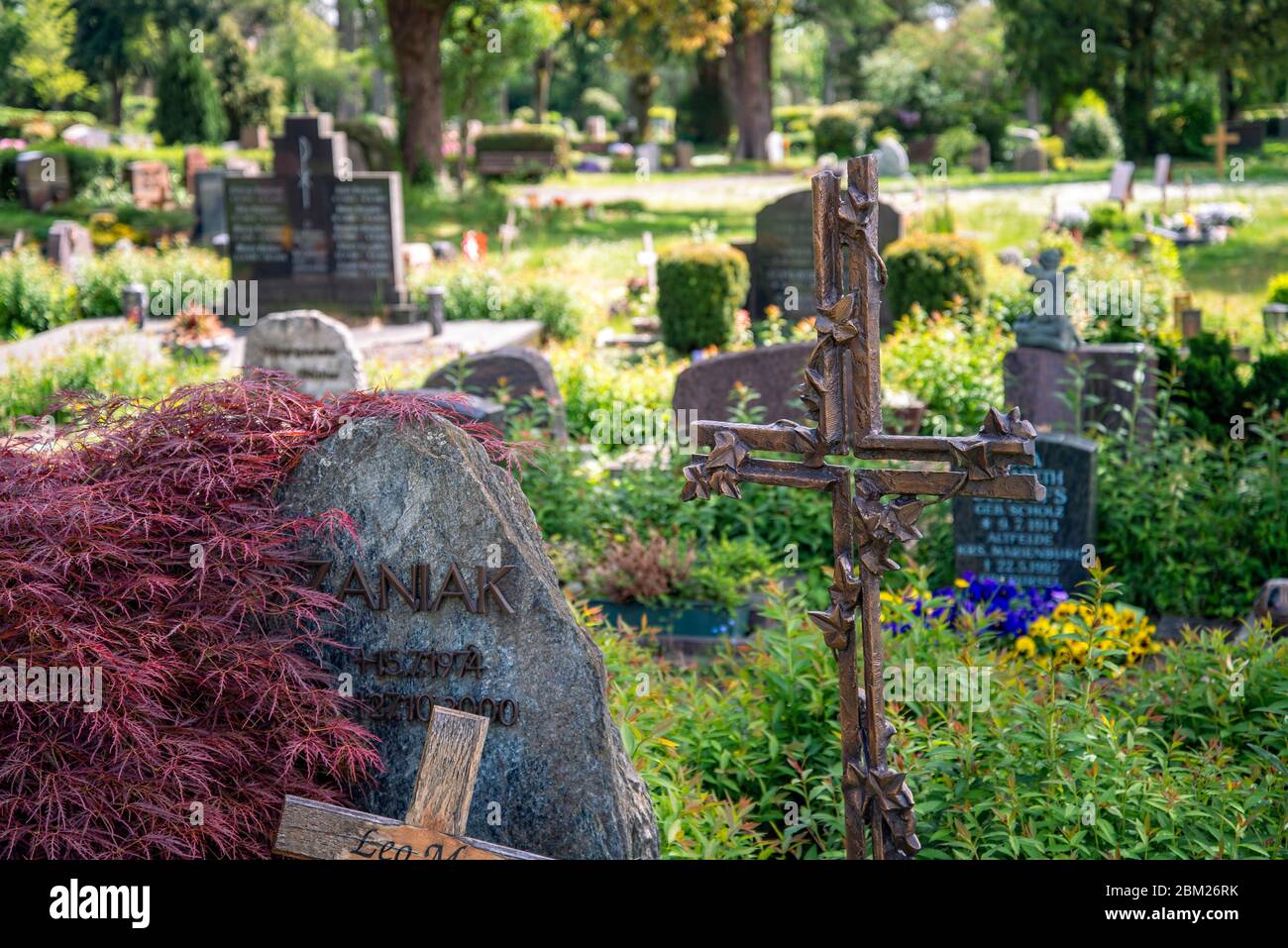 Gräber mit Grabsteinen, Metallkreuz und Blumenschmuck auf dem alten Friedhof von Oberursel bei Frankfurt Stockfoto