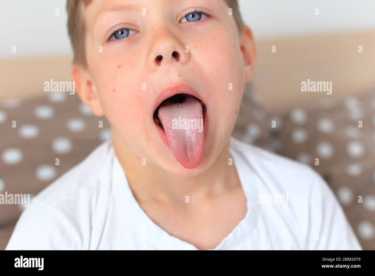 Das Kind zeigt seine lange Zunge aus nächster Nähe Stockfoto