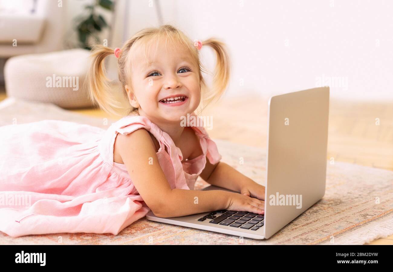 Liebenswert kleines Mädchen mit Laptop auf dem Boden liegen Stockfoto