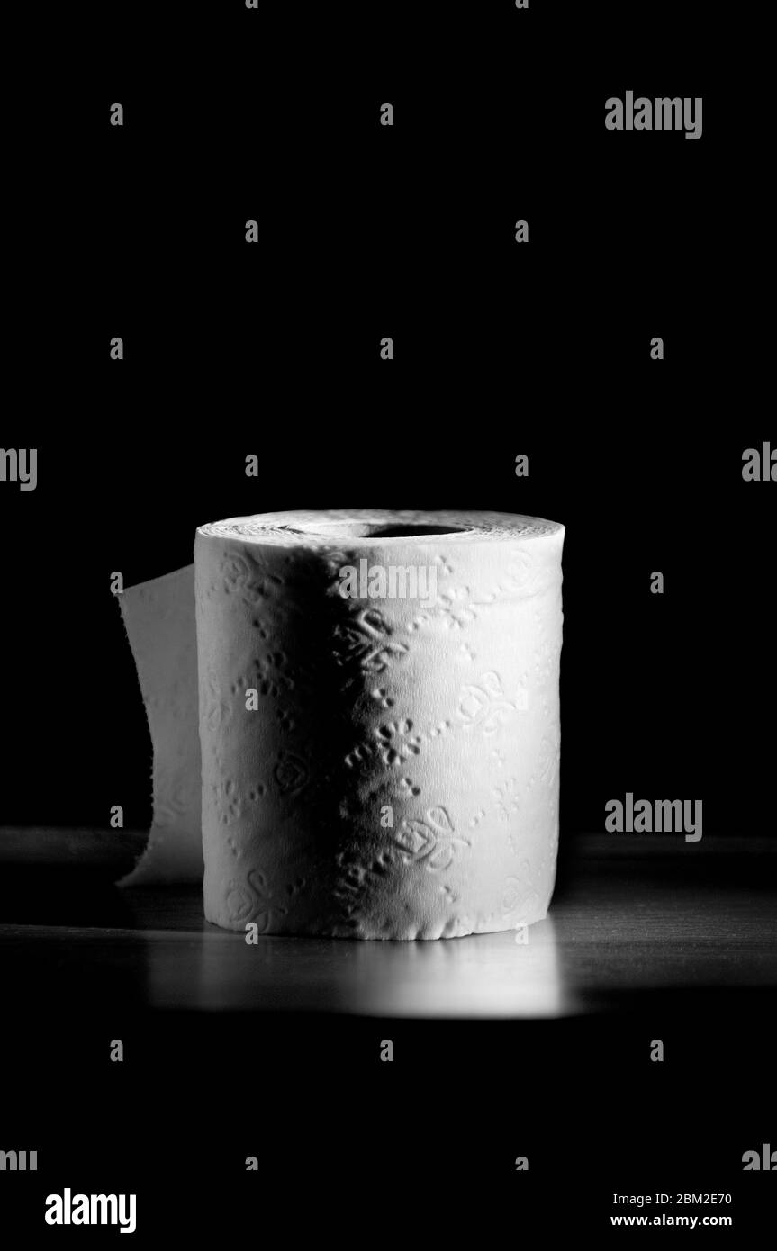 Einzelne Toilettenpapierrolle auf schwarzem Hintergrund Stockfoto