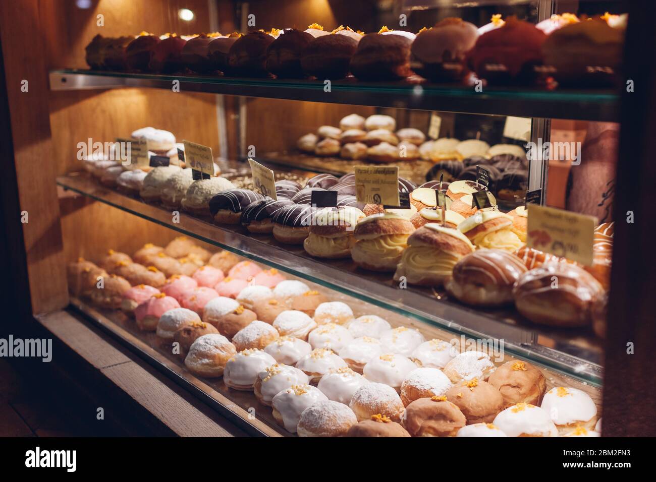 Auswahl an Donuts auf Café-Vitrine. Verschiedene Desserts mit verschiedenen Geschmacksrichtungen auf Regalen im Geschäft. Stockfoto