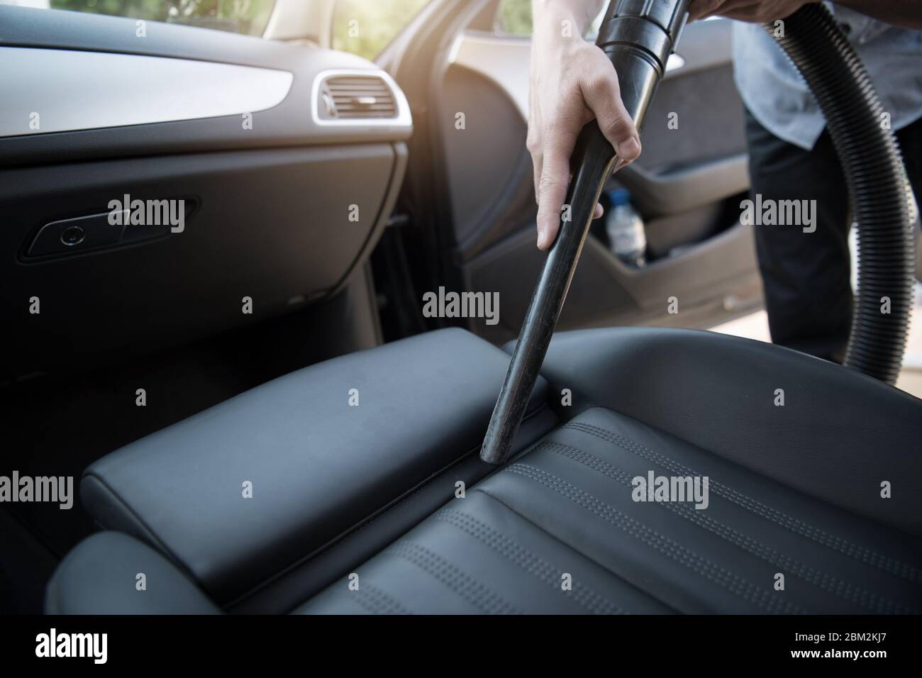 Nahaufnahme Von Männlichen Autobesitzer Reinigung Sitz Des Fahrzeugs Mit Vakuumschlauch Und Befestigung. Stockfoto