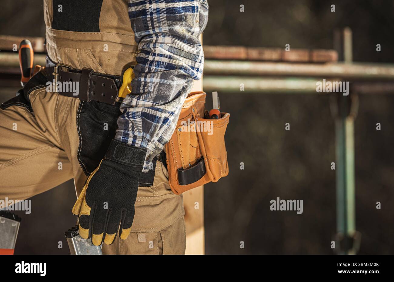 Nahaufnahme Von Bau Männliche Arbeiter Auf Leiter In Der Nähe Von Gerüst Mit Werkzeuggürtel Um Taille Stehen. Stockfoto