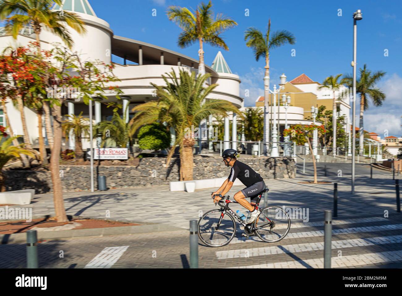 Schwenkschuss eines Radfahrers, der in der Calle Londres am Hotel Jardines de Nivaria während des Notstands von Covid 19 auf Teneriffa, Kanarische Inseln, Stockfoto