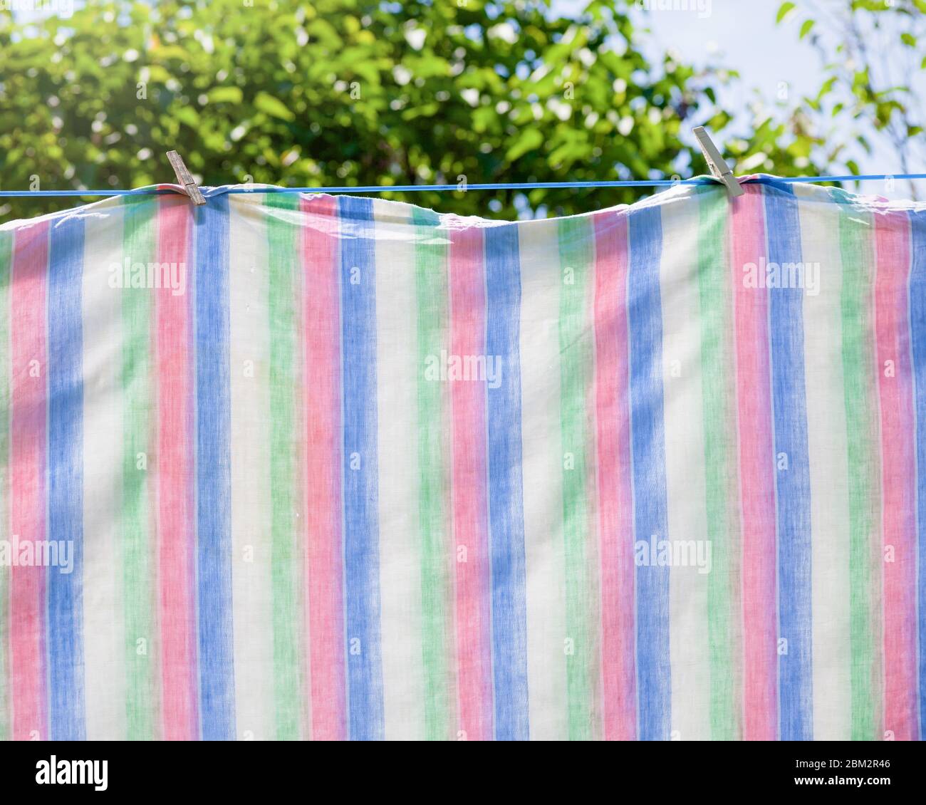 Frisch gewaschene Handtücher oder Laken hängen zum Trocknen an einer Wäscheleine. Stockfoto