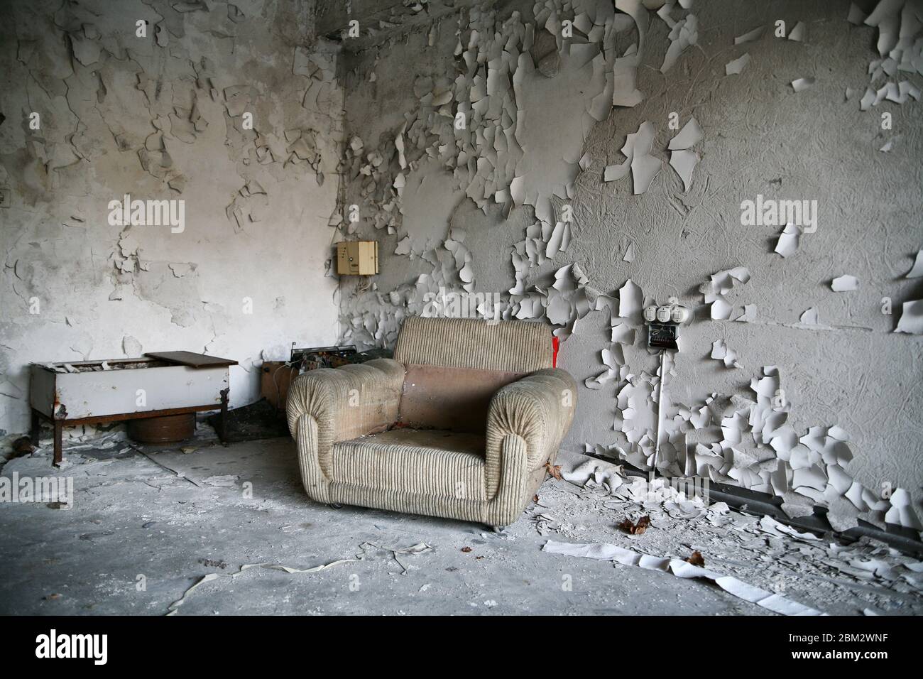 Beschädigter alter Sessel in einem verlassenen Innenraum Stockfoto