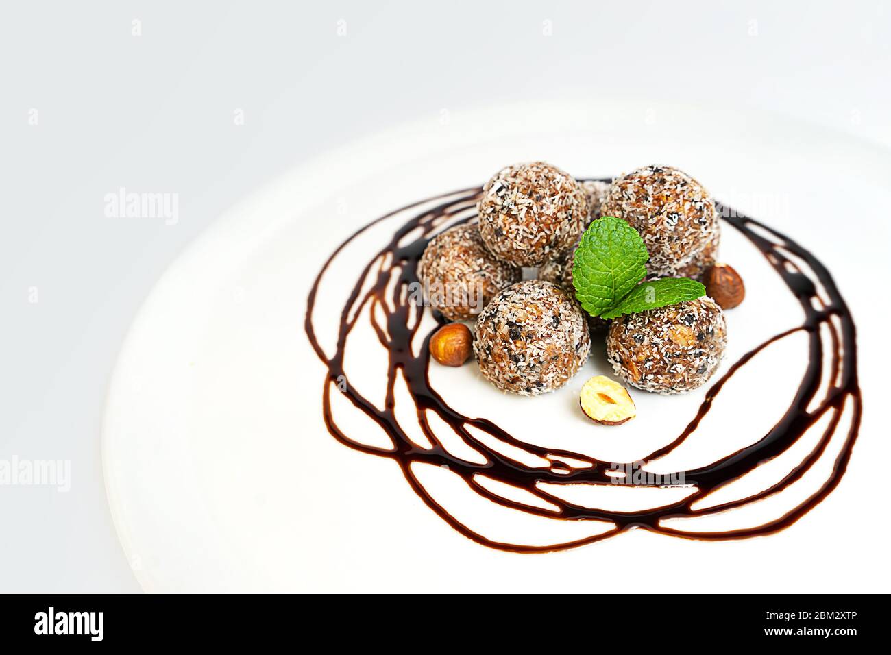Energiebälle oder Energiebeiße mit Hafer, Schokolade und Kokosnuss auf pastellrosa Hintergrund. Gesunde vegane und rohe Ernährung. Richtige Ernährung Konzept. Selektiver Fokus. Kopierbereich. Stockfoto