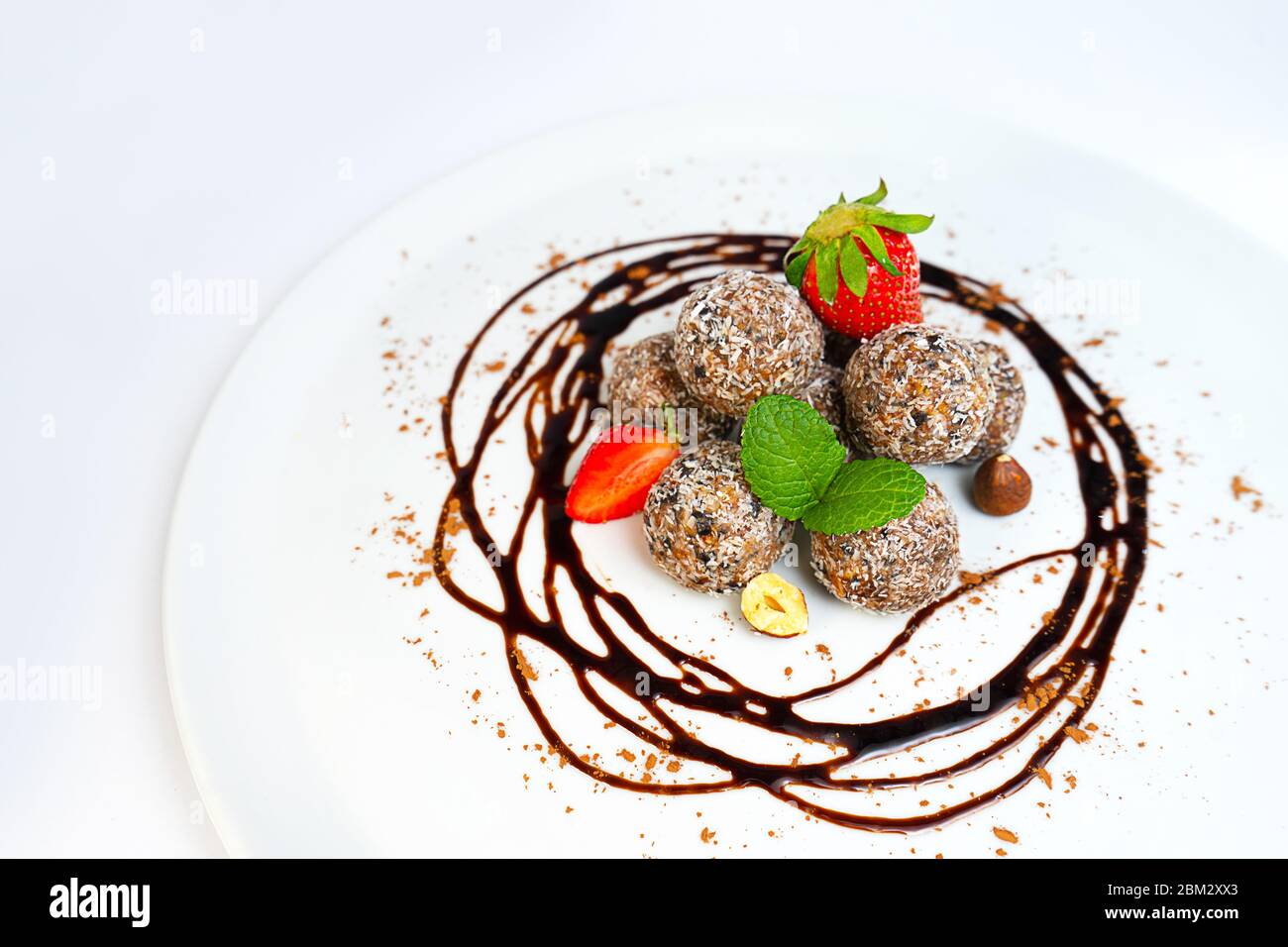 Energiebälle oder Energiebeiße mit Hafer, Schokolade und Kokosnuss auf pastellrosa Hintergrund. Gesunde vegane und rohe Ernährung. Richtige Ernährung Konzept. Selektiver Fokus. Kopierbereich. Stockfoto