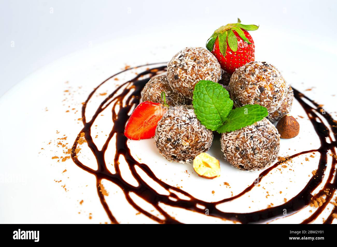 Energiebälle oder Energiebeiße mit Hafer, Schokolade und Kokosnuss auf pastellrosa Hintergrund. Gesunde vegane und rohe Ernährung. Richtige Ernährung Konzept. Selektiver Fokus. Kopierbereich. Stockfoto